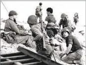  ?? ASSOCIATED PRESS FILE ?? Allied forces battalion members lie low under the fire of Nazi guns on a beach in southern France on D-Day, June 6, 1944, during World War II.