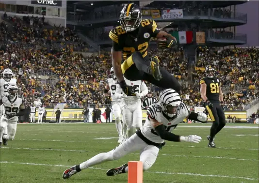  ?? Sports, Section C. Getty Images ?? Steelers running back Najee Harris hurdles Bengals safety Jessie Bates III while scoring on a 19-yard run during the second quarter Sunday at Acrisure Stadium. Mr. Harris rushed for 90 yards and two touchdowns in the Steelers’ loss. More coverage in