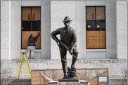  ?? THE COLUMBUS DISPATCH ?? Ohio Statehouse maintenanc­e employees board up the windows of the building behind the United Spanish War Veterans Memorial statue.