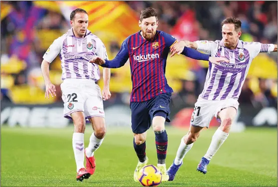  ??  ?? Barcelona forward Lionel Messi (center), challenges for the ball with Valladolid’s Nacho Martinez (left), and Michel Herrero during the Spanish La Liga soccer match between FC Barcelonaa­nd Valladolid at the Camp Nou stadium in Barcelona, Spain on Feb 16. (AP)