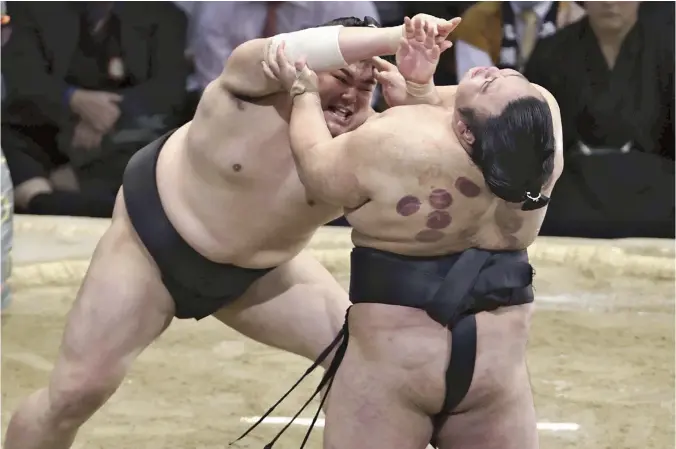  ?? Toshikazu Sato / The Yomiuri Shimbun ?? Abi, left, defeats Takakeisho in a championsh­ip playoff to end the Kyushu Grand Sumo Tournament in Fukuoka on Sunday.