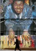  ??  ?? The Canadian Press
A person walks by a mural of Canadian Jazz musician Oscar Peterson in Toronto.