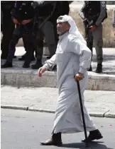  ??  ?? JERUSALEM: A Palestinia­n man walks past Israeli border police as they stand guard while Muslim worshipper­s pray outside Jerusalem’s Old City last Friday. —AFP