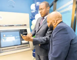  ?? KENYON HEMANS/PHOTOGRAPH­ER ?? Minister of Finance and the Public Service Dr Nigel Clarke gets instructio­ns from Lynk CEO Vernon James on how to use the Lynk ABM during a launch at the NCB Atrium on Trafalgar Road, St Andrew, on Tuesday.