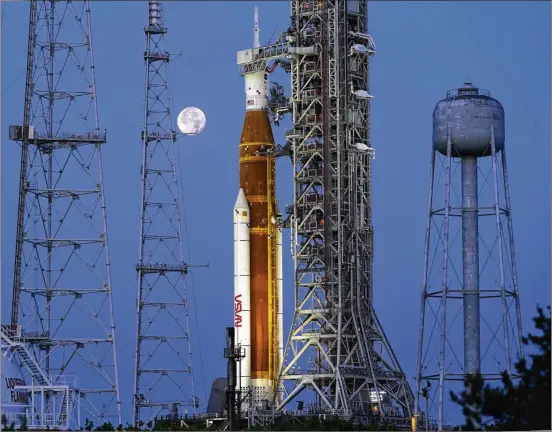  ?? PHOTOS BY JOHN RAOUX/ASSOCIATED PRESS ?? The moon sets in front of the NASA Artemis rocket with the Orion spacecraft aboard on pad 39B at the Kennedy Space Center in Cape Canaveral, Florida, on June 15. With liftoff planned for Monday, the 322-foot rocket will attempt to send an empty crew capsule into a far-flung lunar orbit.