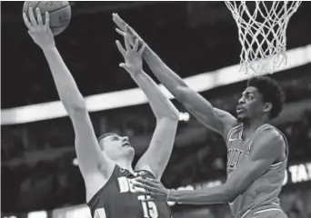  ?? Jonathan Daniel, Getty Images ?? Nuggets center Nikola Jokic takes a shot against the Bulls’ Justin Holiday during Wednesday night’s game at the United Center in Chicago. Jokic scored 21 points and had seven rebounds and five assists in Denver’s 135-102 victory. The Nuggets improved...