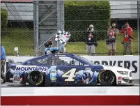  ?? MATT SLOCUM — THE ASSOCIATED PRESS ?? Kevin Harvick waves a checker flag for photograph­ers after winning the NASCAR Cup Series auto race at Pocono Raceway, Saturday, in Long Pond.