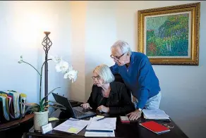  ?? AP/JAE C. HONG ?? Debbie Douglas works on her computer as her husband and business partner, Gary, stands by in their home office in Newport Beach, Calif.