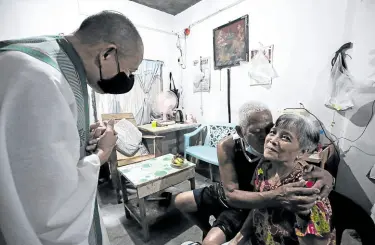  ??  ?? KISS FOR HIS HONEY Fr. Robert Reyes blesses the Santelices couple—retired security guard Jesus and Conchita, who is visually impaired—after they thank him for ministerin­g to them even in the time of the pandemic.