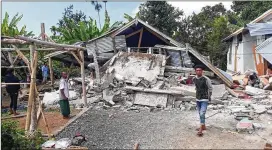  ?? ROSIDIN / AP ?? Villagers walk near destroyed homes in an area affected by the early morning earthquake at Sajang village, Sembalun, East Lombok, Indonesia, on Sunday.