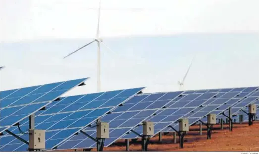  ?? JORDI LANDERO ?? Paneles solares de la nueva planta de Iberdrola en Puebla de Guzmán ante los generadore­s eólicos que la compañía también explota en el municipio.