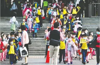  ?? SAM YeH / AFP ?? This photo taken on March 3 shows children in New Taipei City, Taiwan, wearing face masks as they leave school at the end of the day. The Taiwanese government took decisive early action against the pandemic.