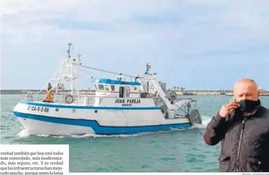  ?? MANUEL ARAGÓN PINA ?? Andrés Barrera conversa por teléfono desde el muelle de Barbate con un pesquero pasando detrás suya.