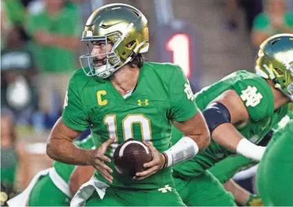  ?? MICHAEL CATERINA/AP ?? Notre Dame quarterbac­k Sam Hartman looks to hand the ball off during the first half of Saturday’s game against Ohio State in South Bend, Ind. The Irish lost 17-14.