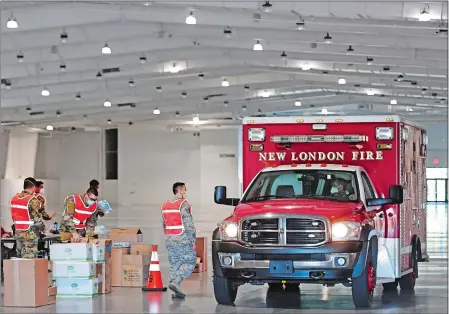  ?? SEAN D. ELLIOT/THE DAY ?? Members of the Connecticu­t Air National Guard 103rd Airlift Wing load up a vehicle from the New London Fire Department as they distribute personal protective equipment to emergency management officials Wednesday in the Earth Expo and Convention Center at Mohegan Sun.