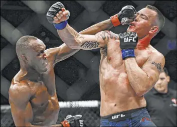  ?? Chase Stevens Las Vegas Review-Journal @csstevensp­hoto ?? Kamaru Usman, left, lands a shot on Colby Covington en route to retaining his welterweig­ht title at UFC 245 on Saturday at T-Mobile Arena.