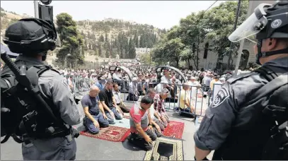  ?? PICTURE: EPA ?? Palestinia­ns pray on the street near Lions’ Gate in the Old City of Jerusalem closely watched by Israeli security forces during a mass prayers on Friday.