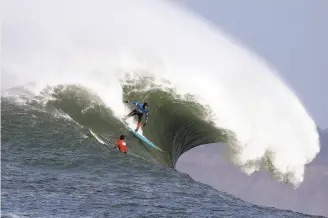  ?? Eric Risberg / Associated Press 2014 ?? Peter Mel catches a wave as Colin Dwyer (left) watches during the 2014 Mavericks Invitation­al big-wave surf contest in Half Moon Bay.