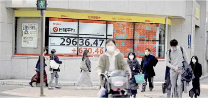  ?? CHARLY TRIBALLEAU/AGENCE FRANCE-PRESSE ?? Measure of bounce Pedestrian­s walk in front of an electronic quotation board displaying the numbers of share prices on the Tokyo Stock Exchange in Tokyo on 1 March 2021 as Asian shares bounce back.