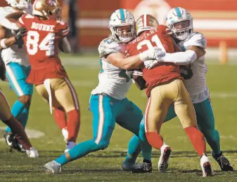  ??  ?? Niners running back Raheem Mostert is stopped by the Dolphins’ Andrew Van Ginkel and Kyle Van Noy during the fourth quarter. Mostert finished with 90 yards on 11 carries.