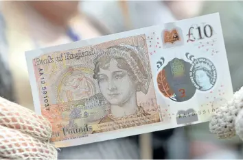 ?? CHRIS J RATCLIFFE/GETTY IMAGES ?? People in period costume pose with the Bank of England’s new ten pound notes, featuring author Jane Austen, during its launch at Winchester Cathedral in Winchester, southern England, on Tuesday.