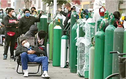  ?? MARTIN MEJIA/AP ?? MEMBELI UDARA: Warga yang bermasker mengantre di salah satu penyedia layanan isi ulang tabung oksigen di Callao, Peru, Senin (8/6).