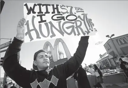  ??  ?? Alex Robles joins dozens of sign-holding protesters Thursday at a rally against low wages for fast-food workers, in front of a McDonald’s in Phoenix.