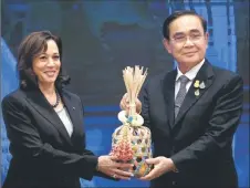  ?? ?? Thailand’s Prime Minister Prayut Chan-o-cha (right) hands a ceremonial woven cha-lom to Harris (left) at the handover ceremony during the APEC summit in Bangkok. — AFP photo