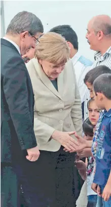  ??  ?? Η Αγκελα Μέρκελ μαζί με τον Αχμέτ Νταβούτογλ­ου χαιρετούν προσφυγόπο­υλα από τη Συρία στο στρατόπεδο προσφύγων του Γκαζιαντέπ της Τουρκίας.
