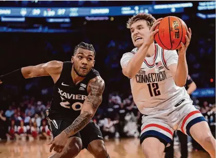  ?? Frank Franklin II/Associated Press ?? UConn’s Cam Spencer (12) protects the ball from Xavier’s Dayvion McKnight (20) during Thursday’s Big East Conference tournament in New York.