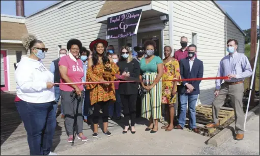  ?? Photo by Sarah Perry ?? Joined by her family and members of the Malvern/Hot Spring County Chamber of Commerce, Crystal Purifoy, center, leads a ribbon cutting ceremony at her business Crystal P. Designs.