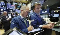  ?? Richard Drew/Associated Press ?? Trader Timothy Nick, center, works with specialist Michael O'Mara on the floor of the New York Stock Exchange Nov. 7.