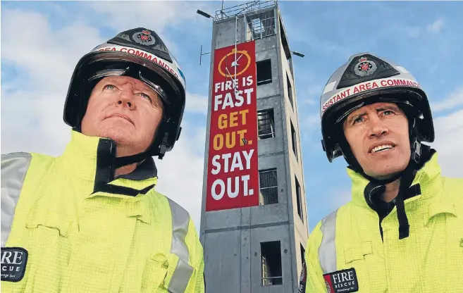  ?? Photo JOHN HAWKINS/FAIRFAX NZ 630961355 ?? Area commander Bruce Stubbs and assistant area commander Julian Tohiariki in front of the Invercargi­ll Fire Station’s new message, which has been painted on its training tower.