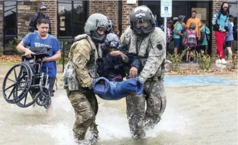  ?? CHRIS MACHIAN/OMAHA WORLD-HERALD VIA THE ASSOCIATED PRESS ?? Nebraska National Guard Sgt. Ray Smith, left, and Staff Sgt. Lawrence Lind carry a disabled man through floodwater­s in Port Arthur, Texas.