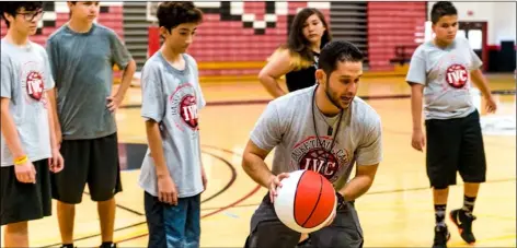  ?? VINCENT OSUNA PHOTO ?? Imperial Valley College men’s assistant basketball coach Hector Vidosola shows a group of young players how to properly perform a layup during the 2018 IVC basketball camp on Thursday at the DePaoli Sports Complex in Imperial.