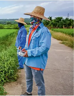  ??  ?? 海南农飞客工作人员用­植保无人机给水稻打药，推动水稻病虫害的绿色­防控工作