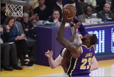  ?? MARK J. TERRILL — THE ASSOCIATED PRESS ?? The Lakers’ LeBron James scores as Nuggets forward Torrey Craig defends during the first half March 6 in Los Angeles.