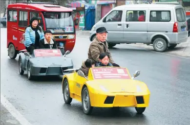  ?? ZUO DONGCHEN / FOR CHINA DAILY ?? Guo Liangyuan and his family go to school in two roadster-shaped electronic cars in a suburb of Zhengzhou, Henan province, on Tuesday. The vehicles, which have a top speed of 40 kilometers per hour and cost around 5,000 yuan ($726) each, were made by...