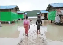  ?? Reuters ?? Muslim residents at Taungpaw walk through the flood to reach the new house built by the Myanmar government in central Rakhine.