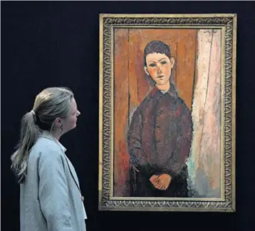  ?? / CHRIS J. RATCLIFFE (GETTY) ?? Una mujer contempla Jeune homme assis, les mains croisées sur les genoux Modigliani, en la sede de Sotheby’s en Londres. (1918), de