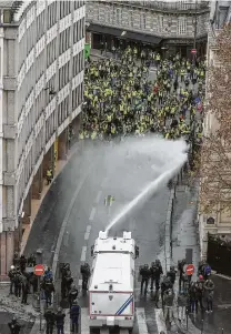  ?? Lucas Barioulet / AFP / Getty Images ?? A water cannon is sprayed at protesters wearing yellow vests near the Arc de Triomphe in Paris. Thousands took to the streets.