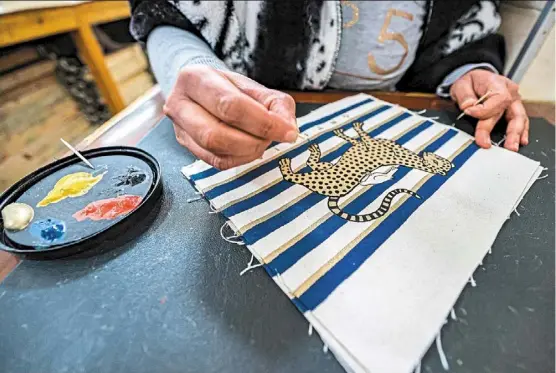  ?? ?? a worker painting a stenciled cloth at the Malaika Linens factory in Cairo. — Photos: Khaled desouki/afp