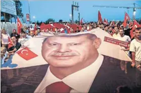  ?? Photo: Osman Orsal/Reuters ?? Resolute: Pro-government demonstrat­ors hold a giant image of President Erdogan. The nation’s government sent low-ranking officials — including Ankara’s deputy mayor — to greet Biden at the airport.