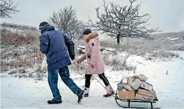  ?? ?? Two Ukranians pull a sledge loaded with distribute­d items at a humanitari­an centre in Bakhmut as they have to walk about 8 km to get home on February 1, 2023, amid the Russian invasion of Ukraine. (Photo by YASUYOSHI CHIBA / AFP)