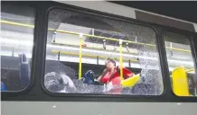  ??  ?? A member of the media stands near a shattered window on a bus Tuesday in Rio de Janeiro, Brazil. Two windows were shattered when rocks, or possibly gunfire, hit the bus carrying journalist­s.