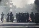  ??  ?? Iranian police officers block a street as garbage cans are set on fire in Tehran.