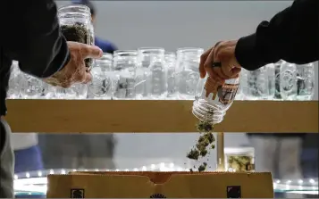  ?? JAE C. HONG / ASSOCIATED PRESS ?? Two undercover Los Angeles County sheriff’s deputies dump marijuana into an evidence bag during a raid at an illegal marijuana dispensary in Compton, Calif., on March 15. The number of outlaw dispensari­es in the county greatly outnumbers about 150...