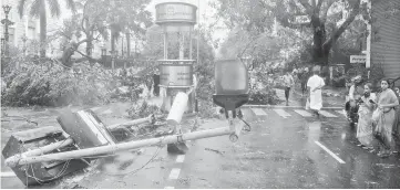  ??  ?? Indian residents stand near debris on a street in Chennai as Cyclone Vardah approaches the Indian coast. — AFP photo