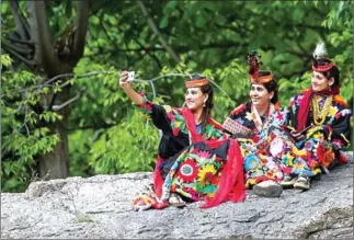  ?? AFP ?? A Kalash woman takes a selfie with her friends during a break as they celebrate ‘Joshi’.