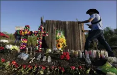  ?? ERIC GAY — THE ASSOCIATED PRESS ?? Roberto Marquez of Dallas adds a flower a makeshift memorial at the site where officials found dozens of people dead in an abandoned semitraile­r containing suspected migrants, Wednesday in San Antonio.